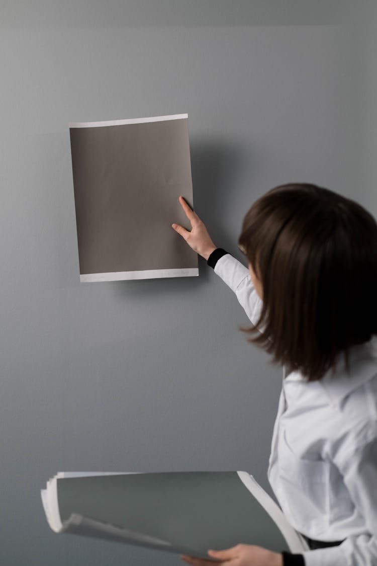 A Woman In White Long Sleeve Shirt Holding Gray Papers