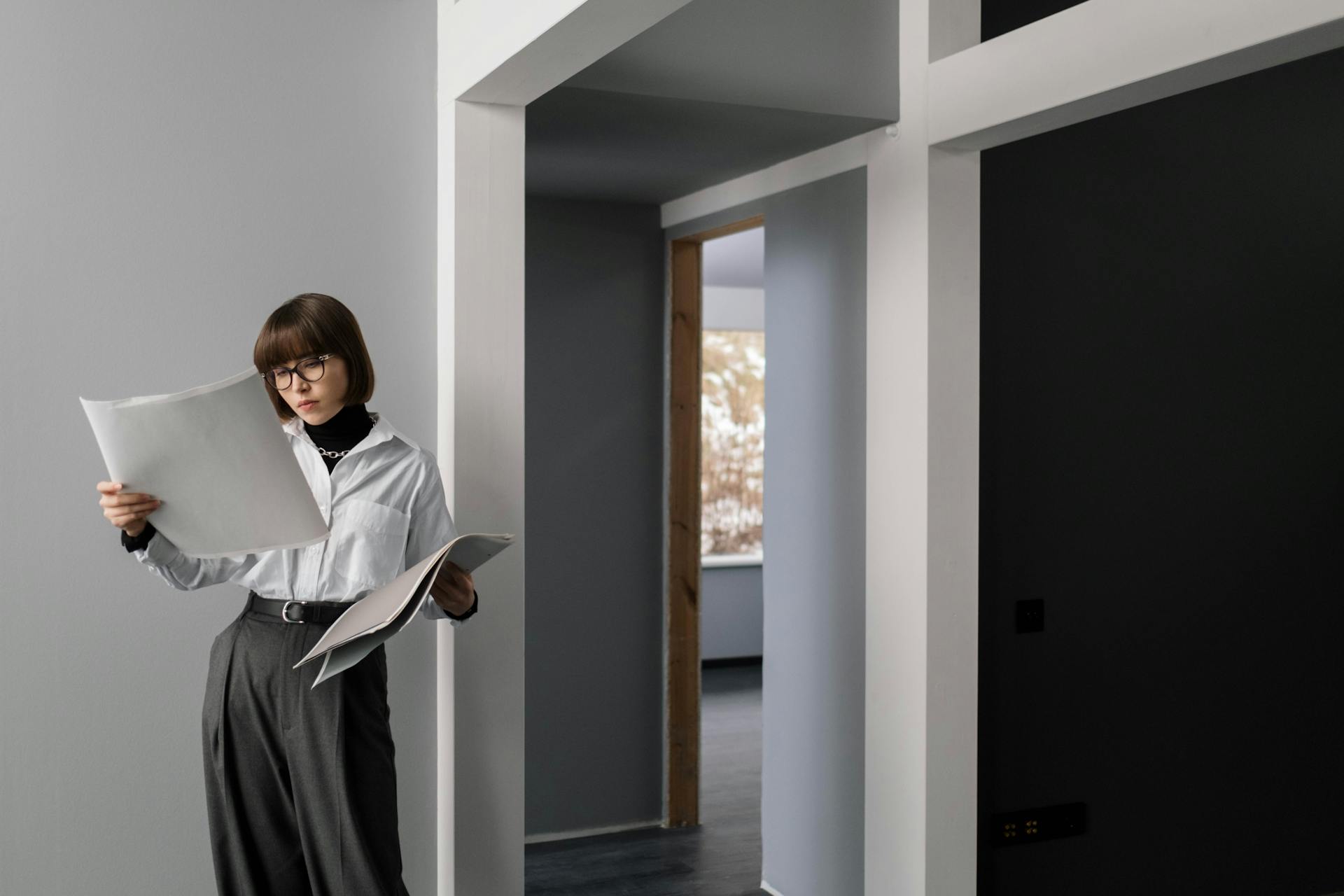 Businesswoman reviewing architectural plans in a modern apartment interior.