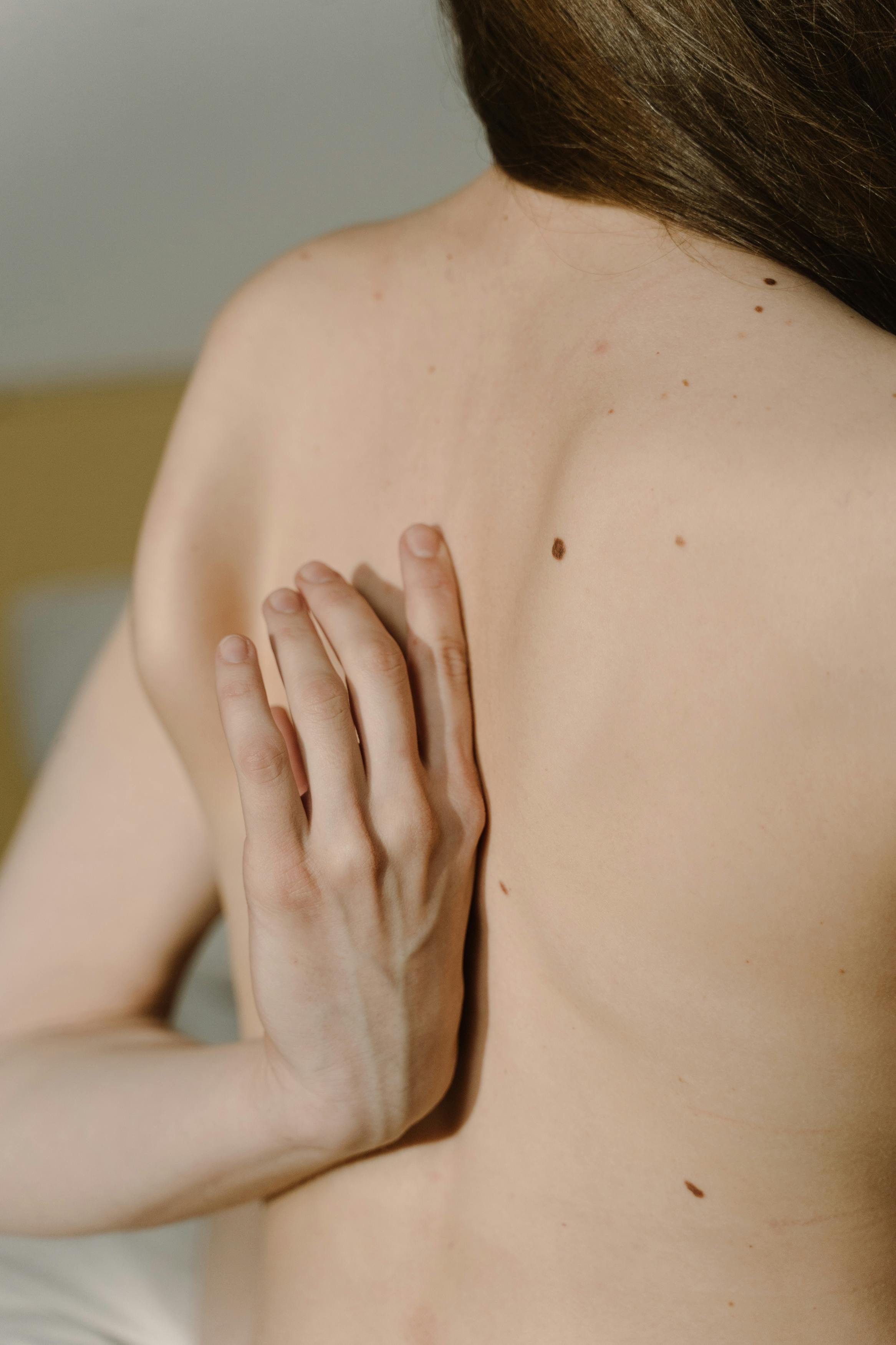 a shirtless woman touching her back