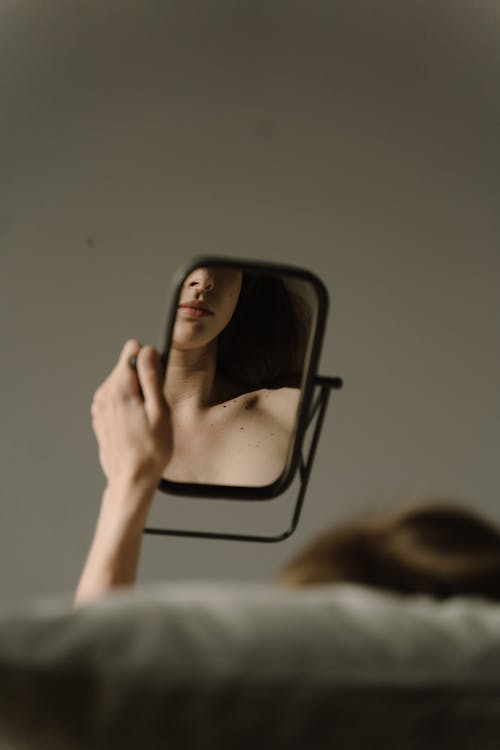 Woman Sitting on a Sofa Looking at her Reflection on a Mirror