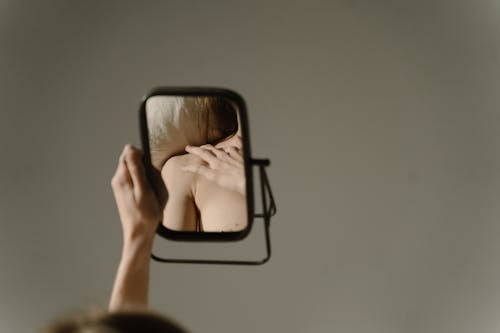 Woman Lying in Bed and Looking at her Shoulder in a Mirror 