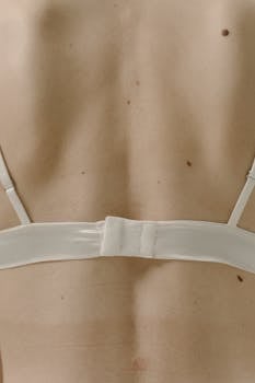 Elegant close-up of a woman's back wearing a white satin bra, showcasing fashion photography.
