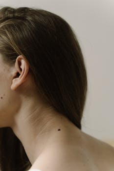A detailed shot of a woman's neck focusing on a small mole. Minimalist and natural aesthetic.