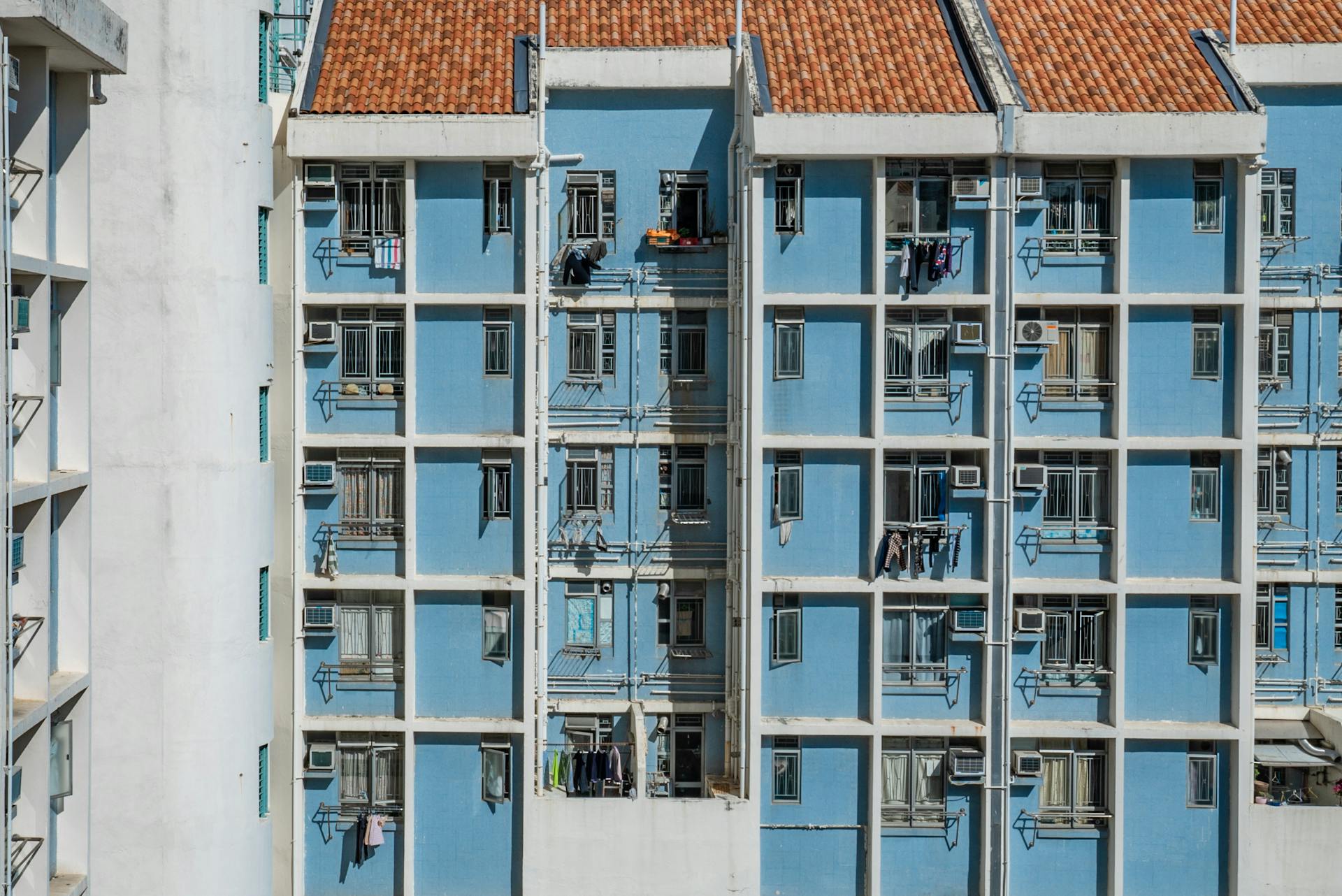 Exterior view of a blue residential building in Hong Kong with tile roof and hanging clothes.