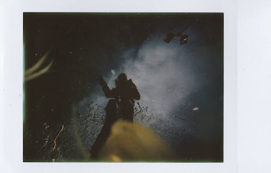Moody reflection of a person in a puddle on a city street at night.