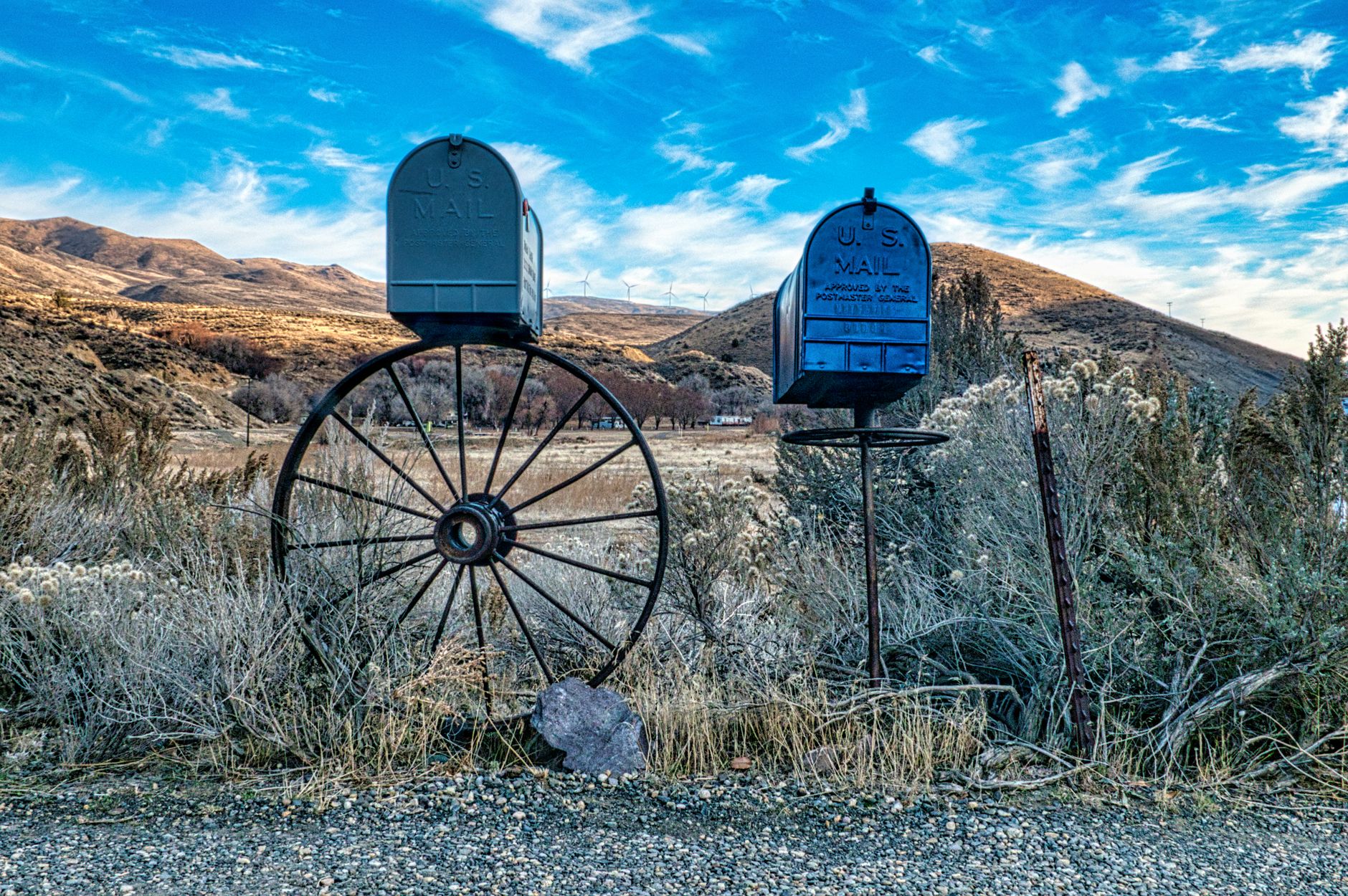 Scenic view of rustic mailboxes with wagon wheel in rural Huntington, Oregon landscape.