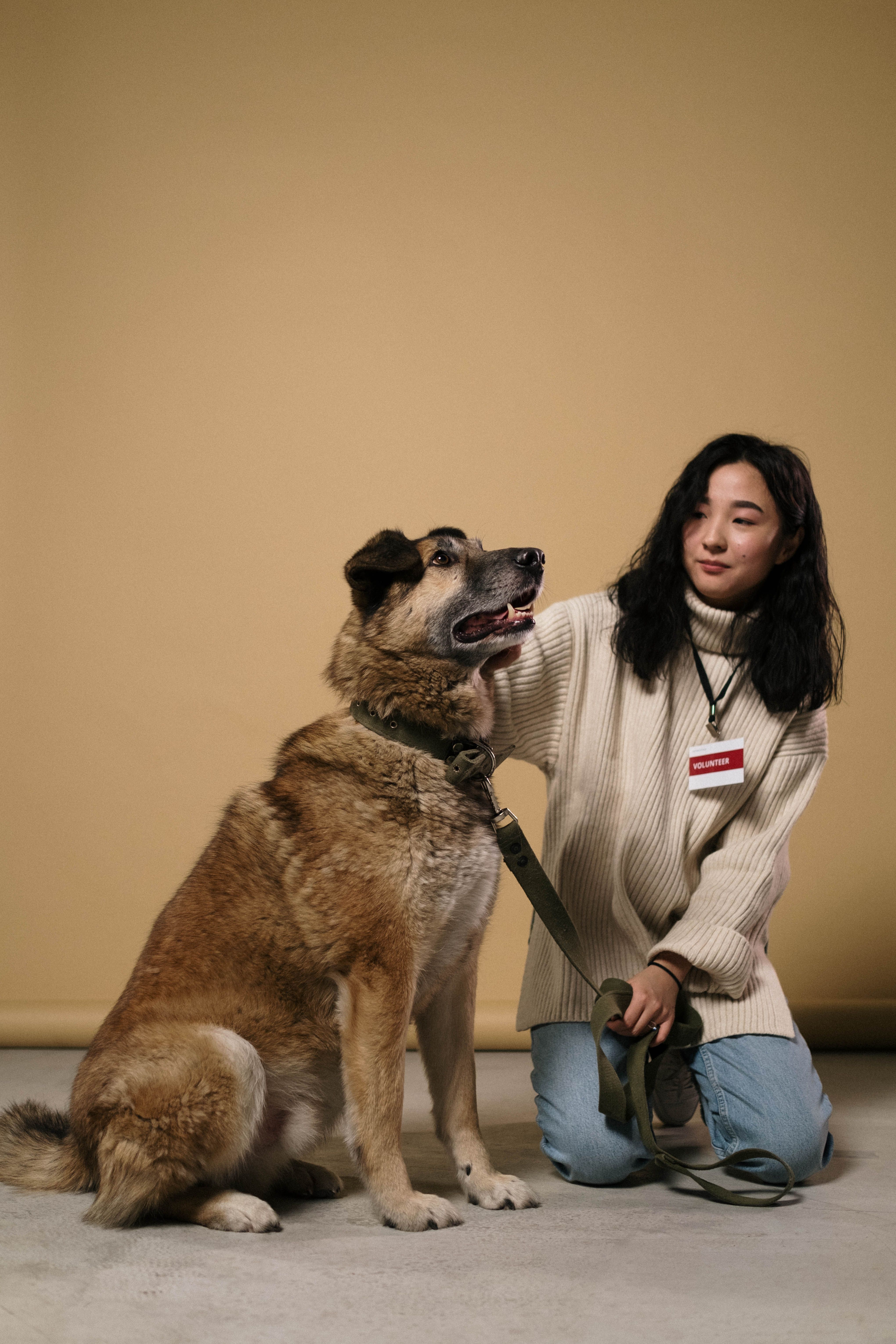 Portrait of a woman sitting with a large dog in a cozy studio environment.