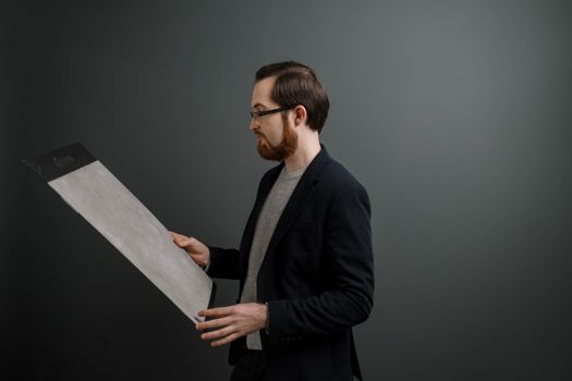 Adult male observing a large paint sample in a studio setting, dressed in formal attire.