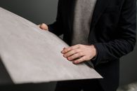 Close-up of a man in business attire examining a large gray panel indoors.