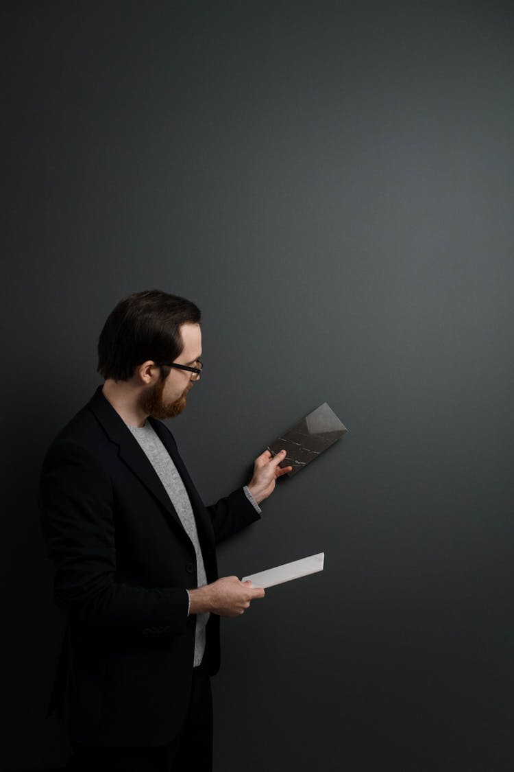 Man Comparing A Sample With A Greenish Gray Wall