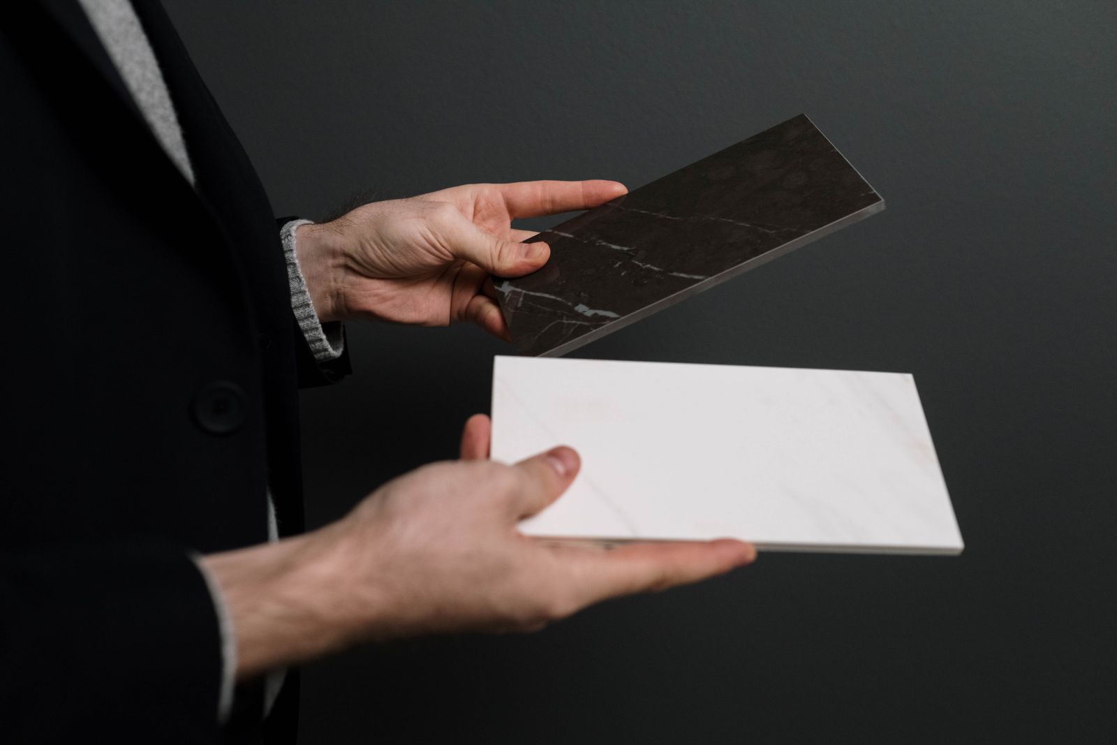 Hands holding two contrasting marble and stone tile samples
