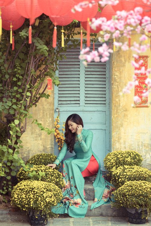 Free Beautiful woman in traditional dress sitting surrounded by vibrant plants and decor. Stock Photo