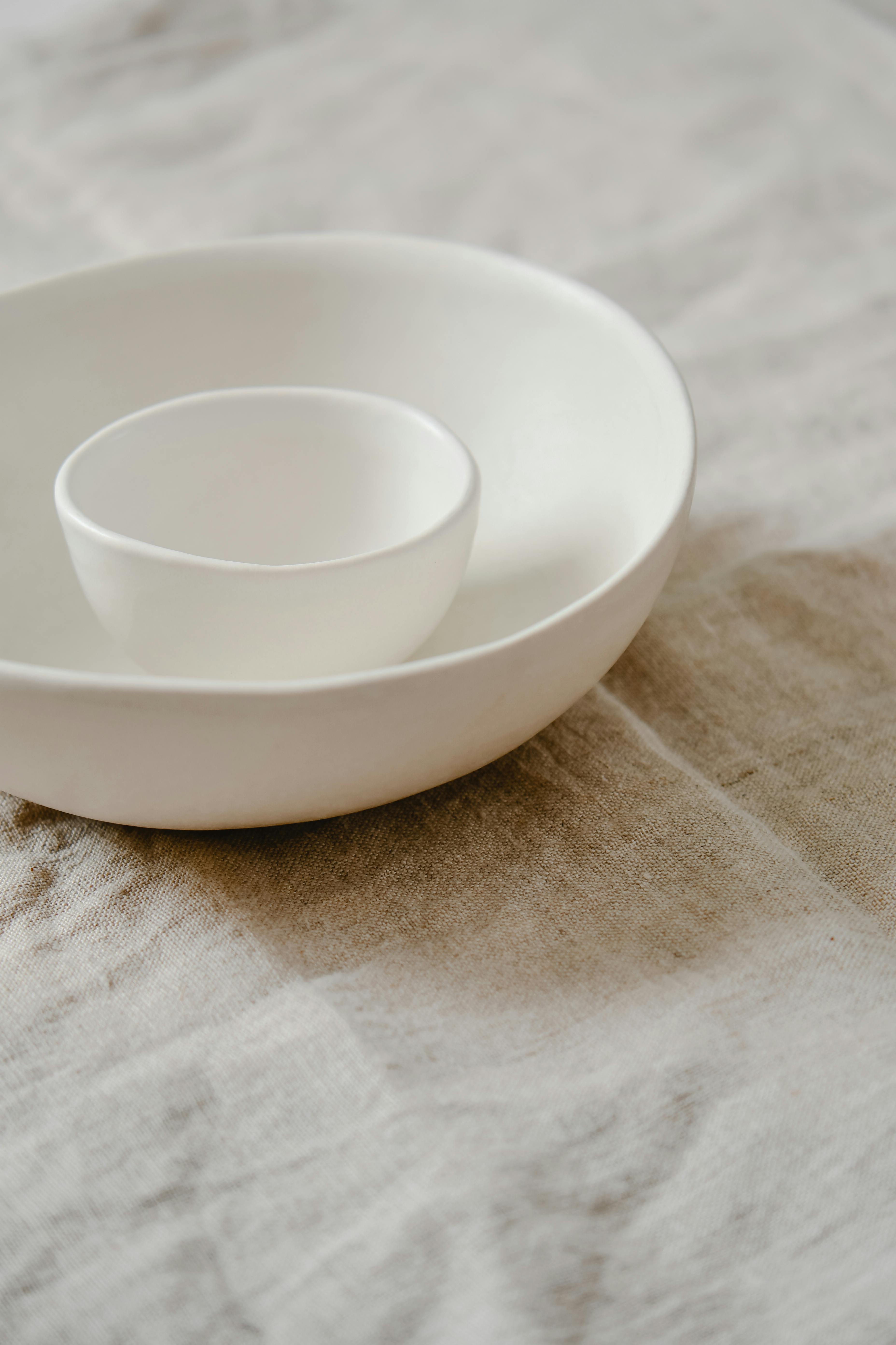 Elegant minimalist white ceramic bowls nested on a neutral linen surface. Perfect for Japandi decor.