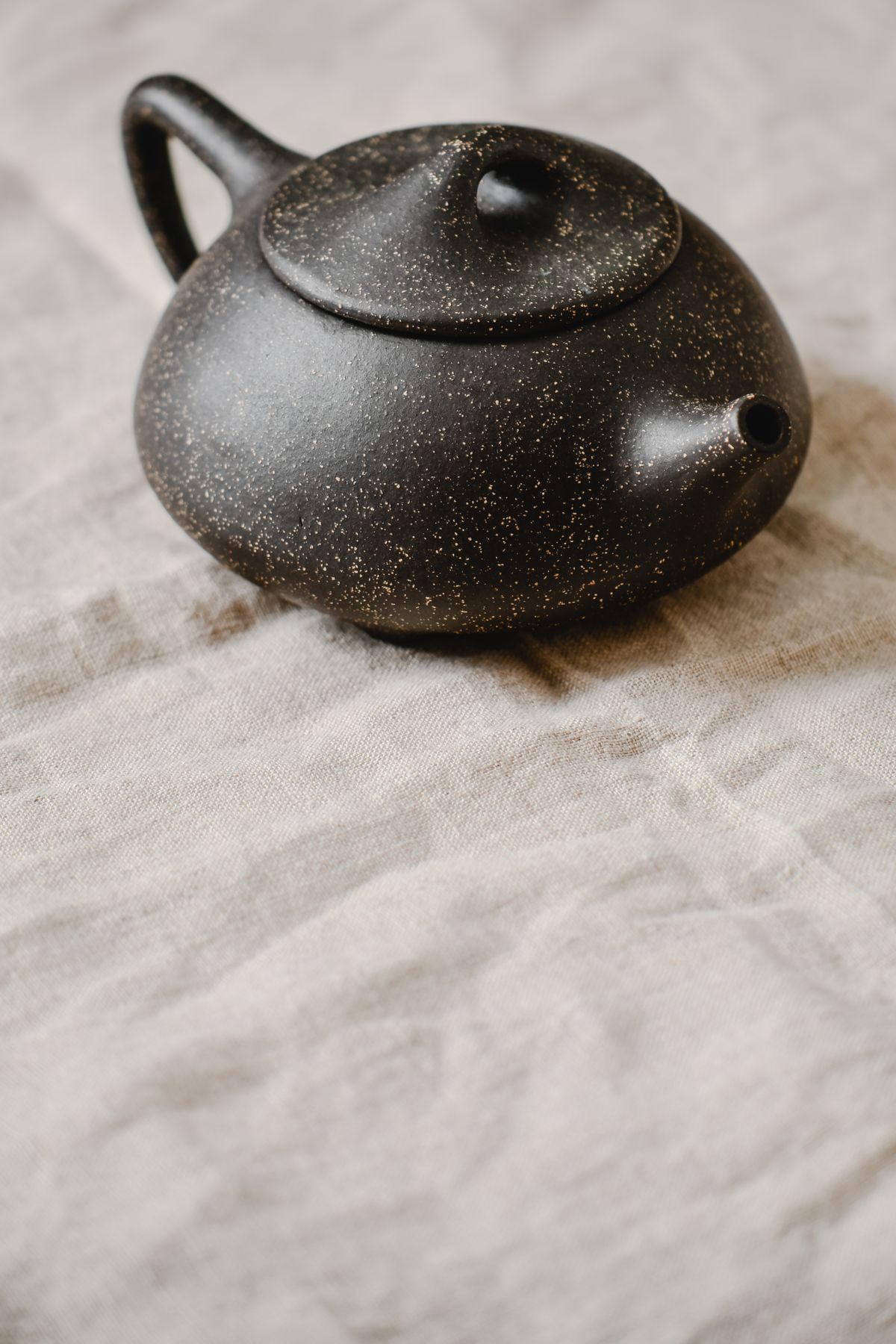 Matte black stoneware teapot on linen