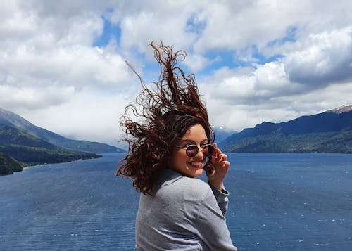 A Woman in Gray Long Sleeves Wearing Sunglasses while Looking Over Shoulder