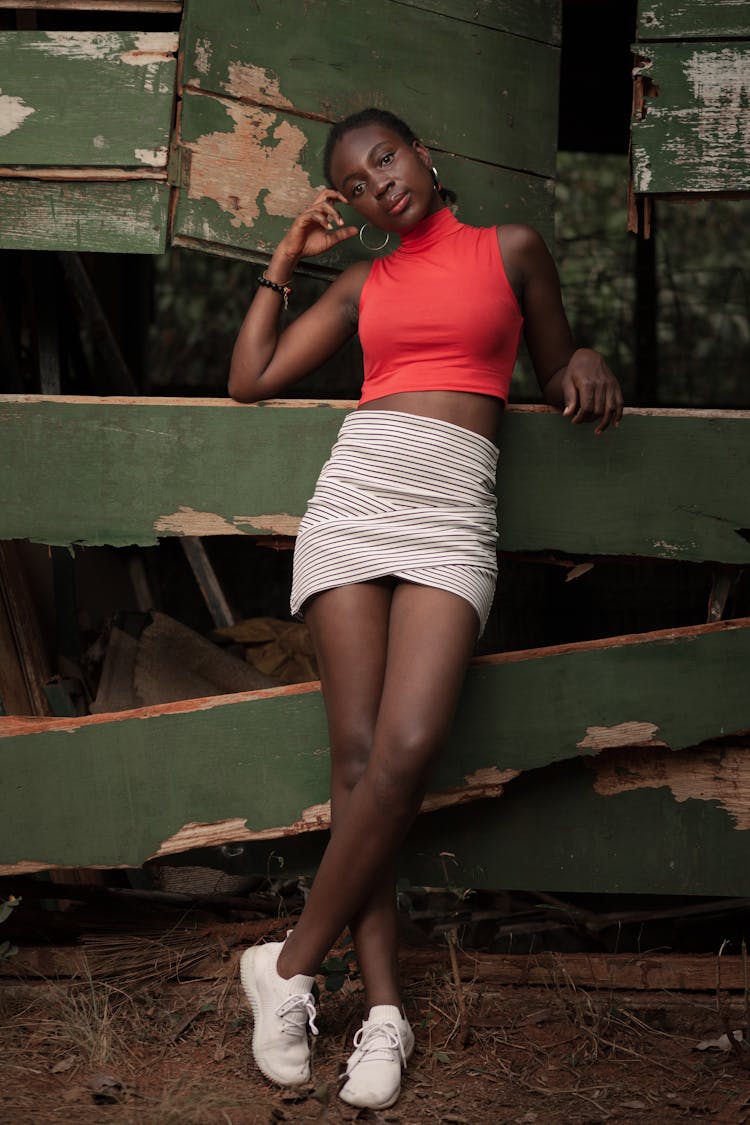 Fashionable Young Ethnic Lady Leaning On Weathered Wooden Fence In Barn