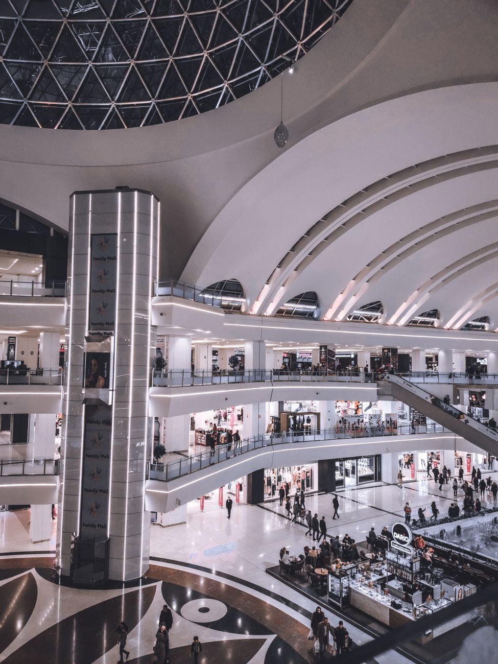 Discover the sleek interior design of a modern shopping mall featuring multi-levels and a geometric dome ceiling.