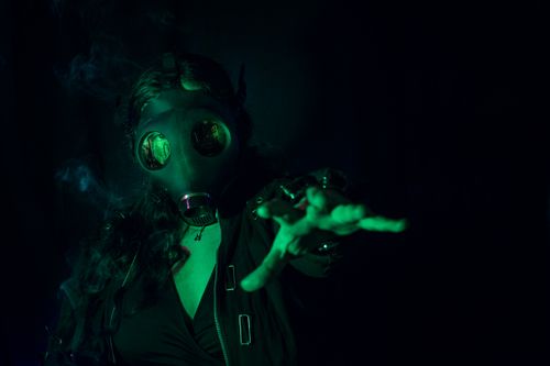 Free Dark and mysterious studio portrait of a person in a gas mask, illuminated by green light, evoking a surreal atmosphere. Stock Photo