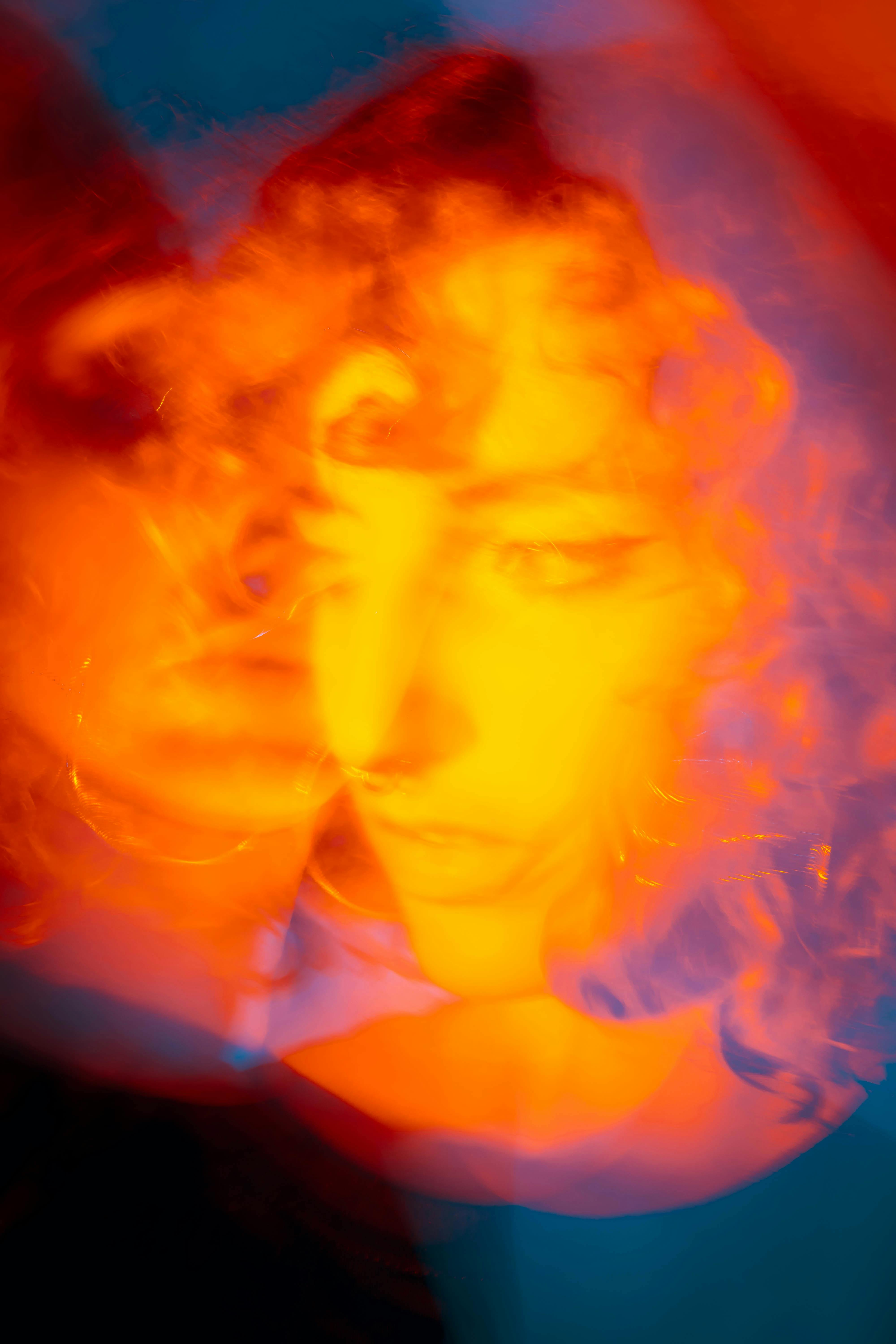 Artistic double exposure portrait using vibrant orange and red tones creating a dreamlike effect.