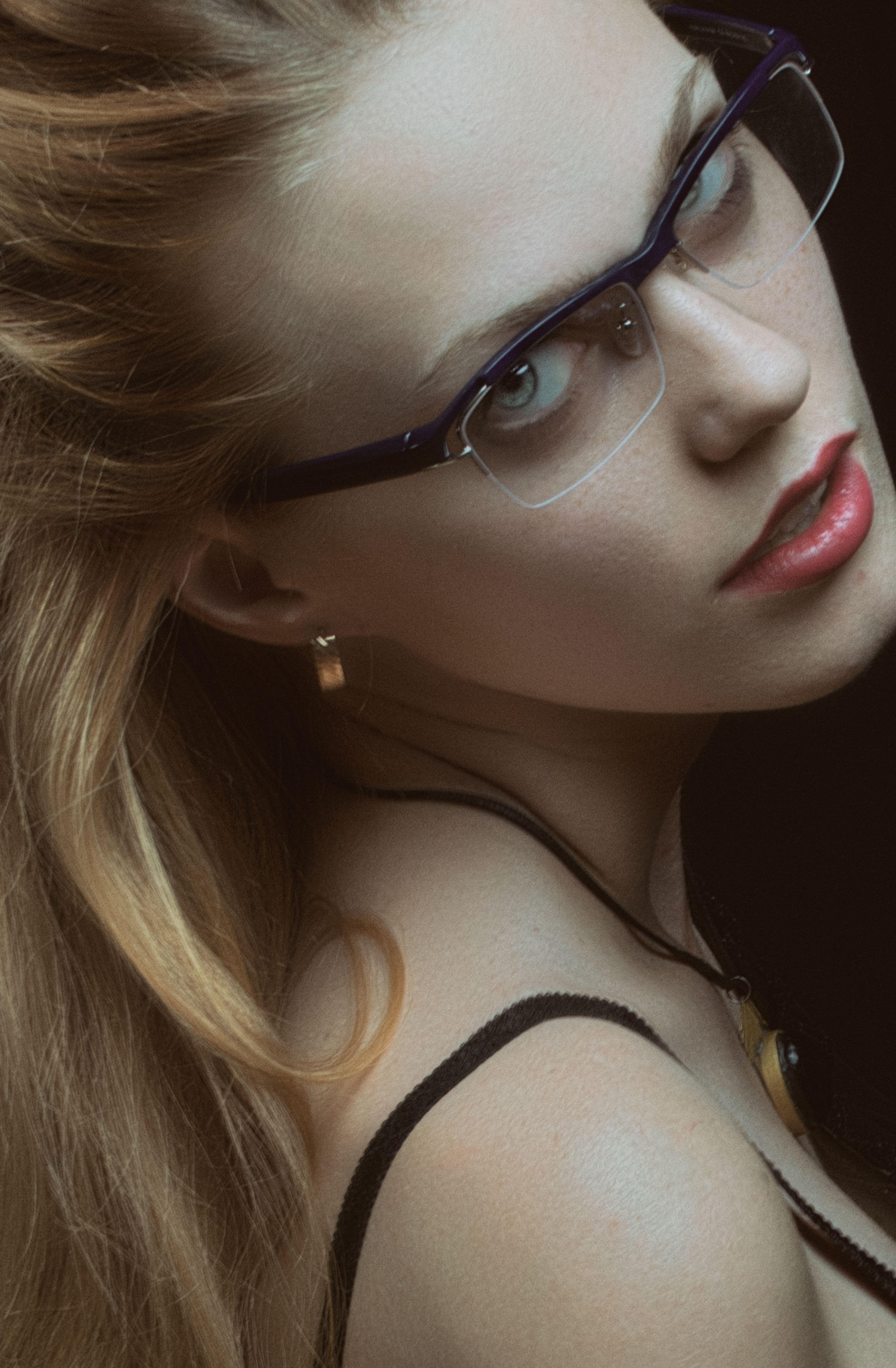Close-up of a woman with blonde hair and eyeglasses in an elegant pose.