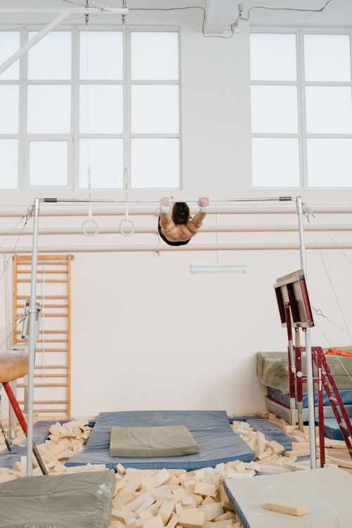 Free A male gymnast performs on parallel bars in a well-equipped indoor gym training space. Stock Photo