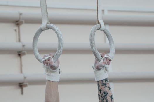 Close-up of hands gripping gymnastic rings, showcasing training essentials and focus.