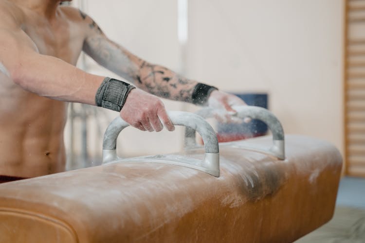 A Gymnast Holding Onto A Pommel Horse