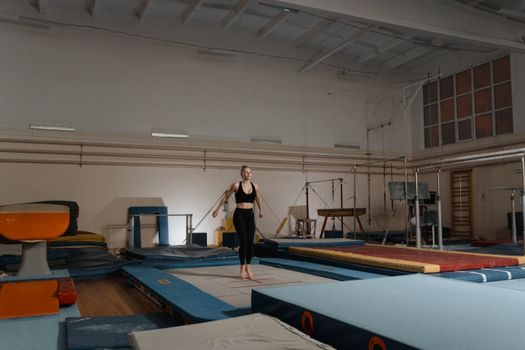 A young female gymnast practicing on gymnastics equipment indoors, showcasing balance and agility.