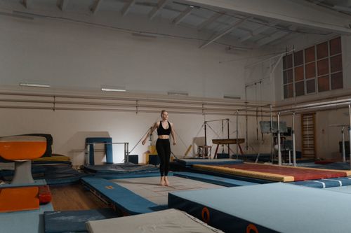 Free A young female gymnast practicing on gymnastics equipment indoors, showcasing balance and agility. Stock Photo