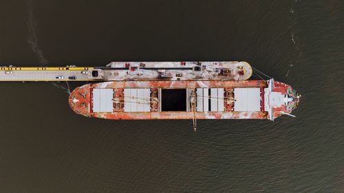 Free Drone view of barge moored on rippled ocean near dock with vehicles in harbor Stock Photo