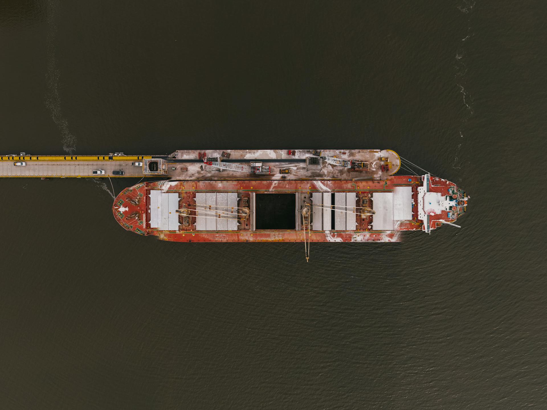 Aerial shot of a large cargo ship docked at a pier, showcasing industrial maritime transport.