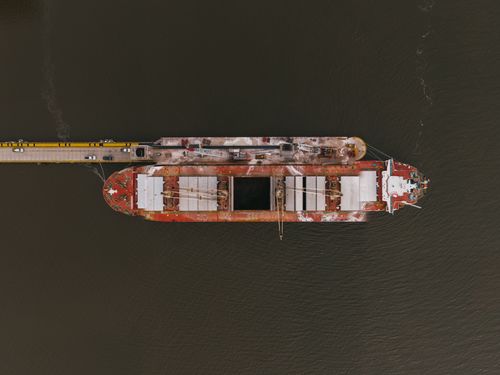 Free Drone view of aged steel ship with rusty surface on calm water of river Stock Photo