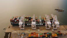 Cargo ship near pier with lifting cranes