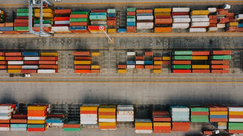 Drone view of various colorful cargo containers placed in rows on asphalt in daytime