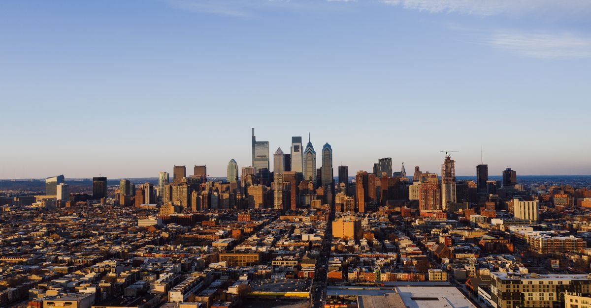 Drone view of contemporary city with many different houses under bright blue sky with clouds