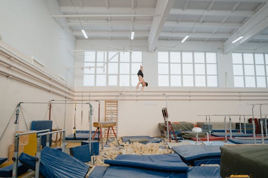 A male gymnast practicing on the parallel bars in a well-equipped gymnasium, focusing on strength and balance.