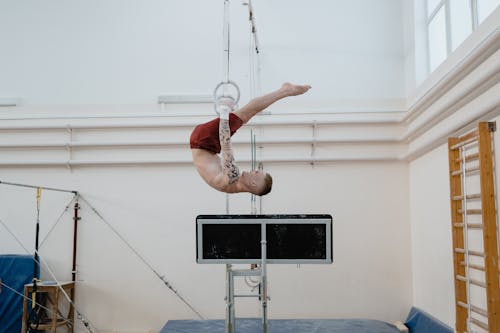 A Man Hanging Upside Down on Gymnastics Rings