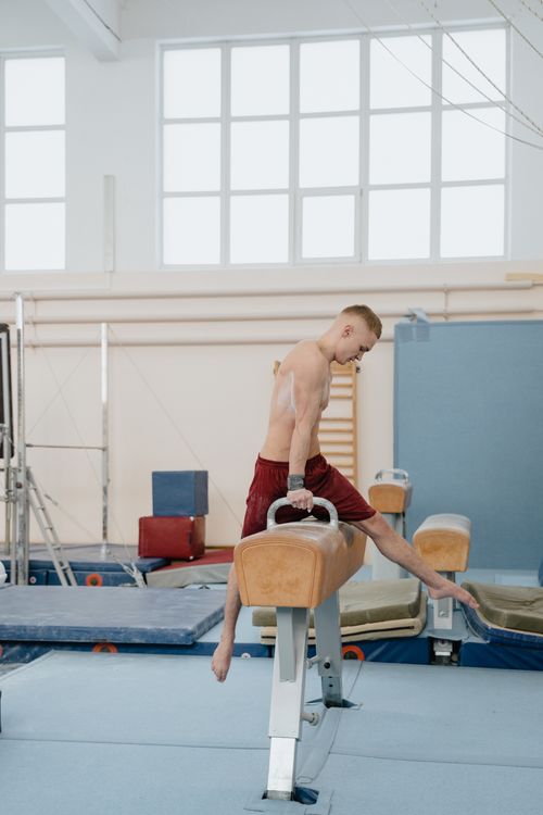 Free Young male gymnast performing on pommel horse in an indoor gym setting, showcasing skill and balance. Stock Photo