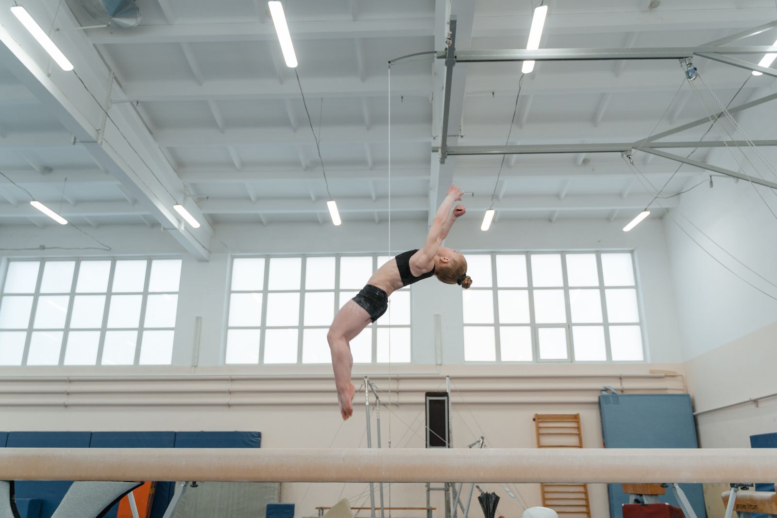 Gimnasta haciendo una acrobacia sobre la viga de equilibrio
