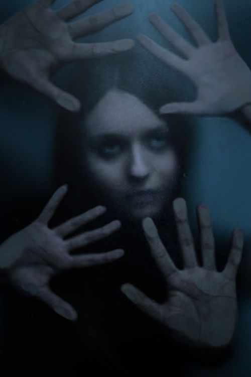 Free A haunting image of a woman pressing her hands against a glass surface, creating a mysterious and eerie atmosphere. Stock Photo