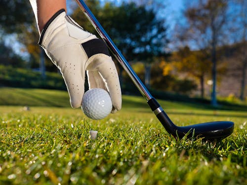 Person Putting Golf Ball on a Tee