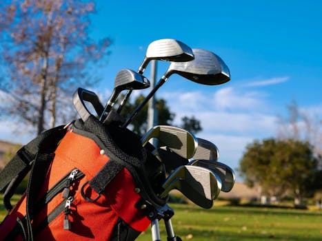 Close-up of a golf bag with clubs on a sunny day outdoors on the golf course.