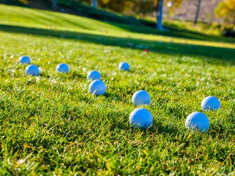Golf balls scattered on a vibrant green fairway under sunny skies.