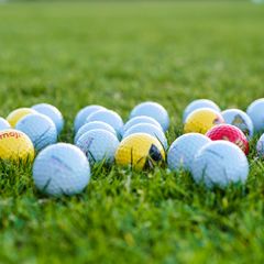White and coloured golf balls in the grass