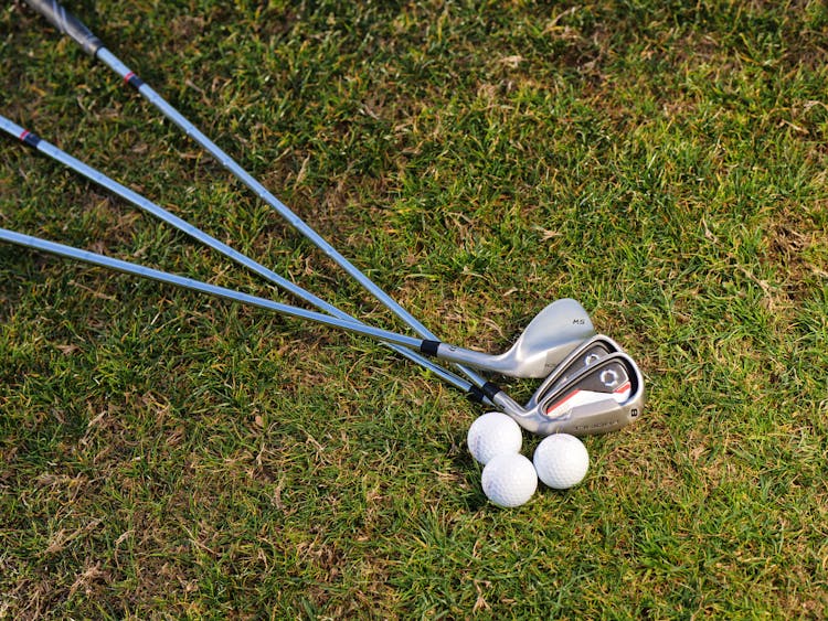 Golf Irons And Balls On Green Grass Field