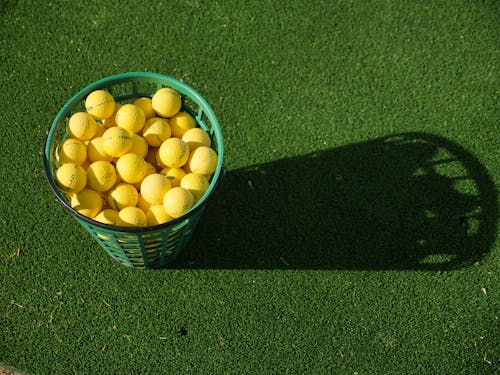 Photo of Yellow Golf Balls in Green Basket