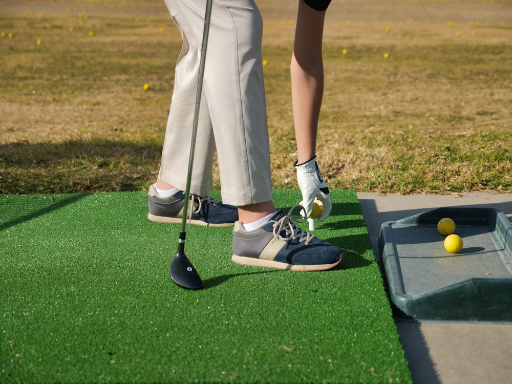 Person putting a golf ball on a tee