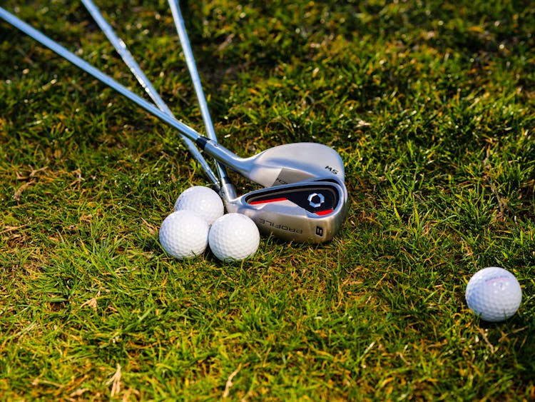 Golf Balls And Golf Clubs On Green Grass