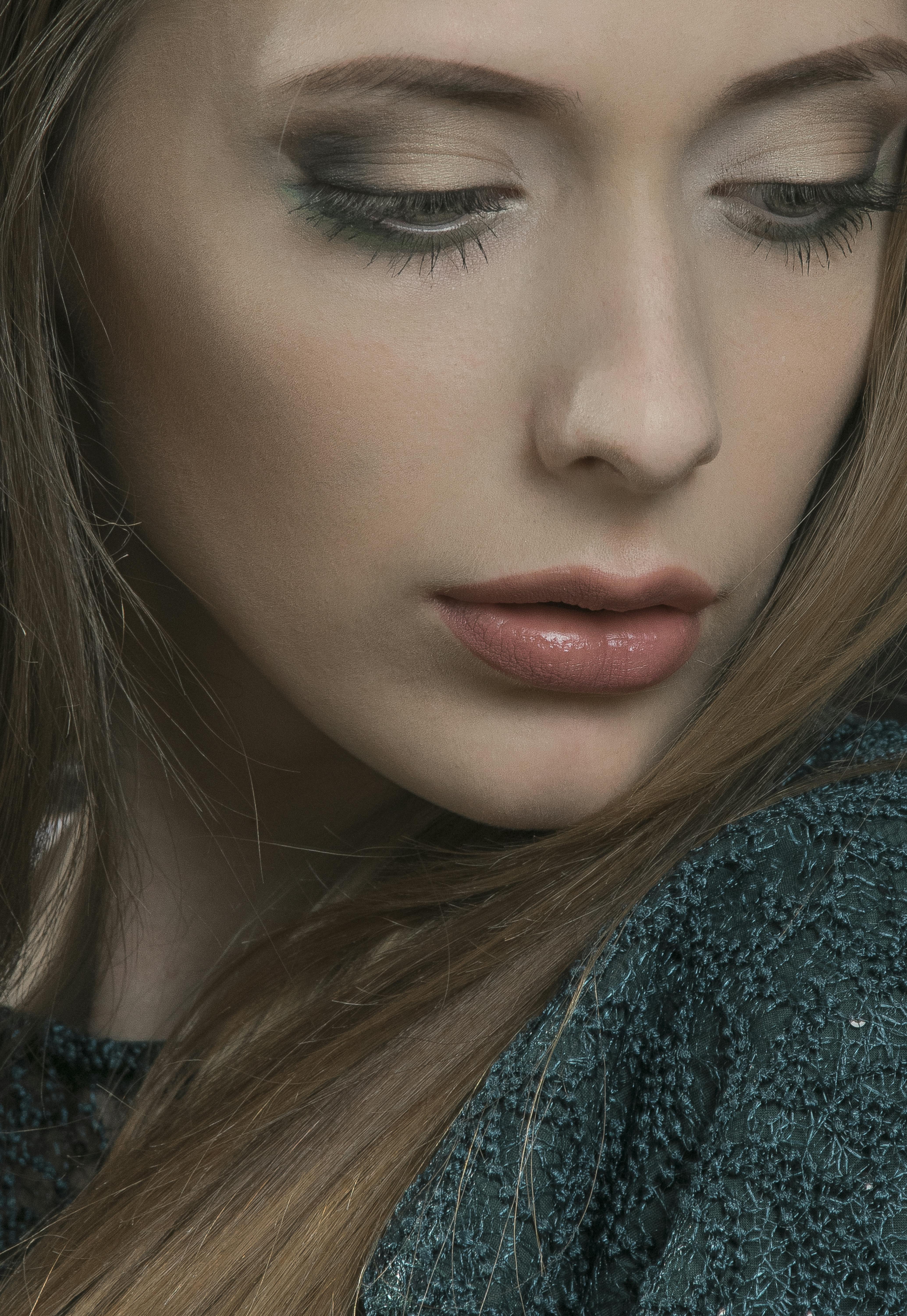 Close-up portrait of a woman with calm expression, highlighting her natural beauty in soft lighting.