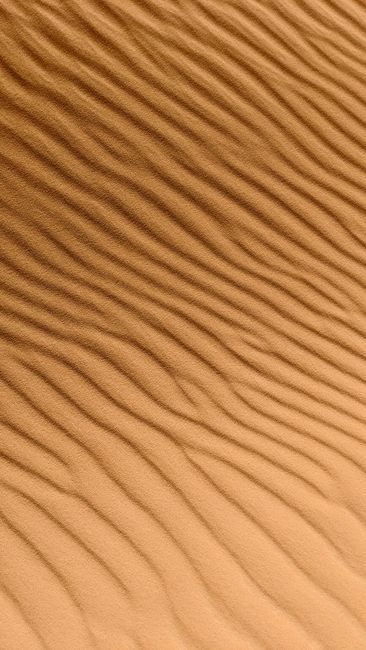 From above of backdrop representing sandy land with wavy surface and loose texture in daytime